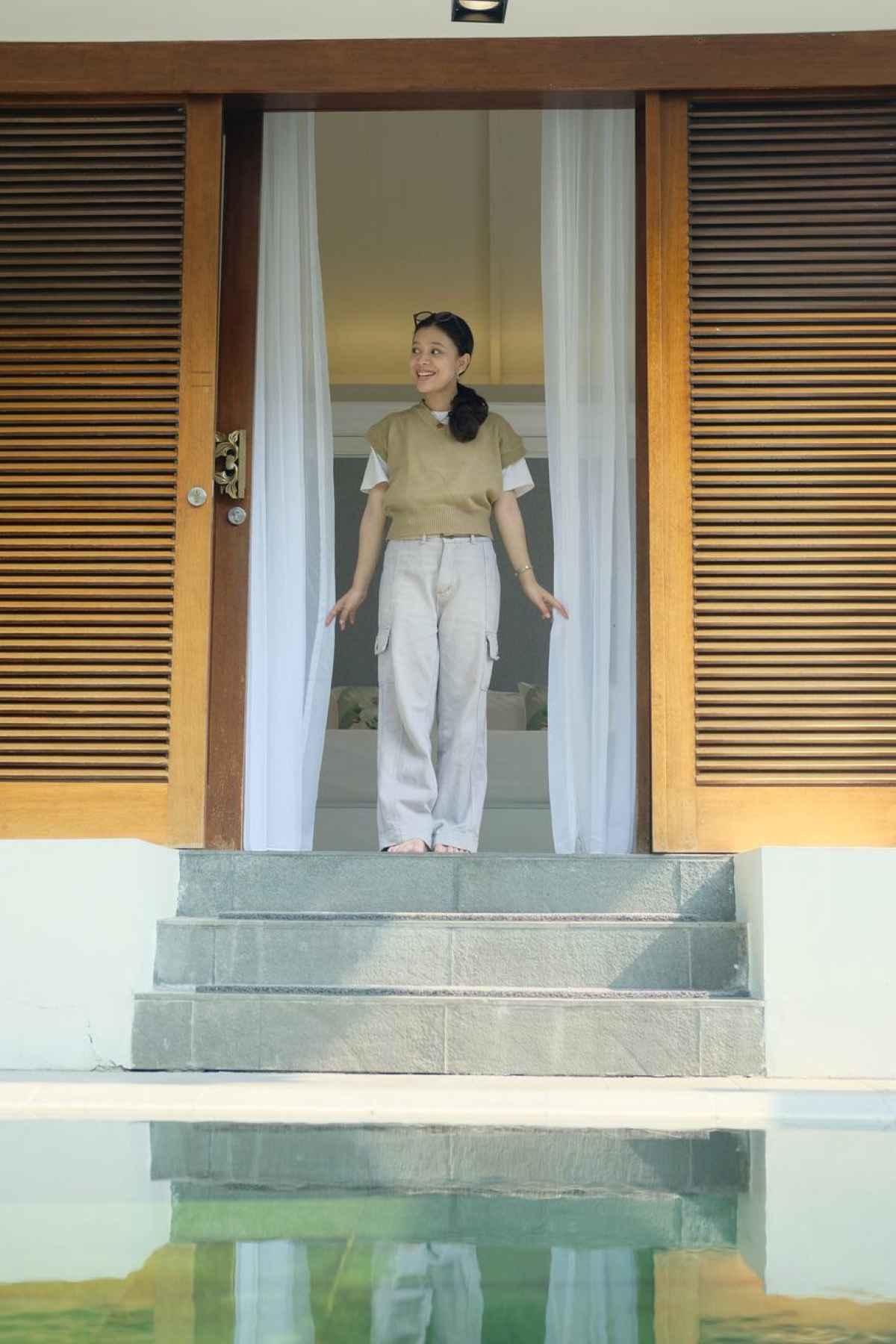 A guest at the bedroom threshold facing the pool