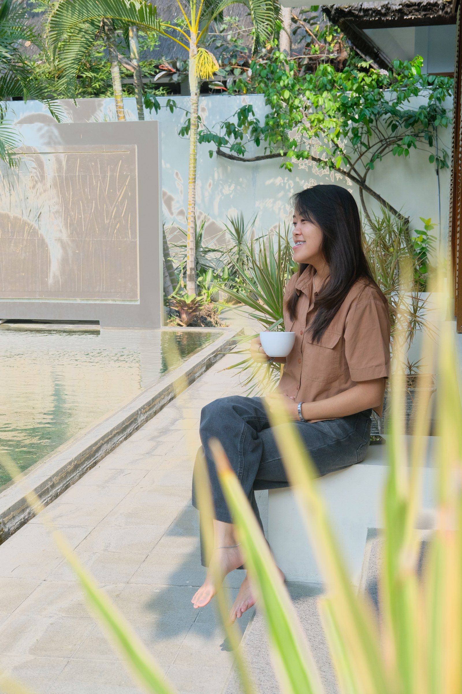 A woman sitting at the pool's edge holding a teacup.