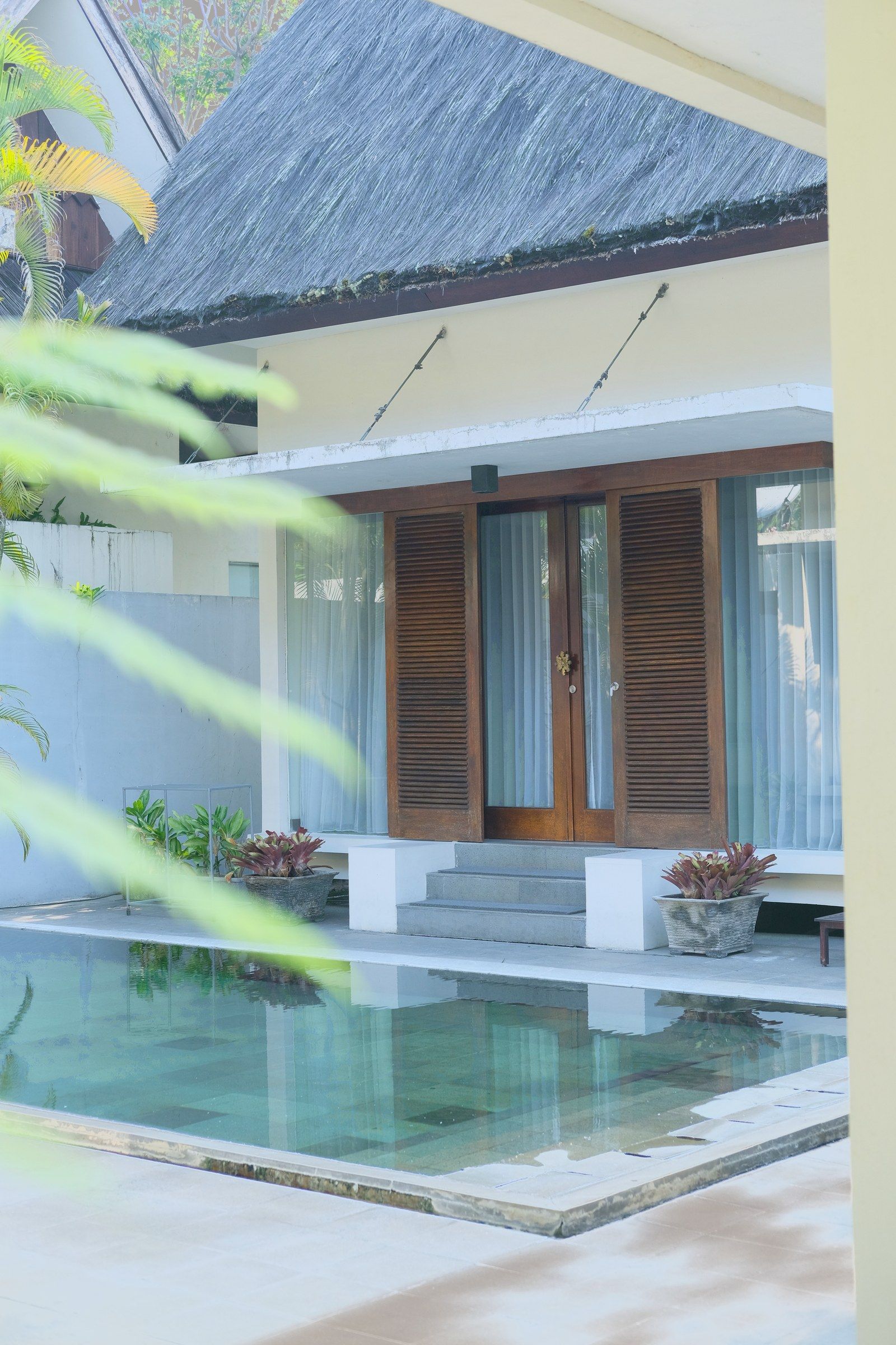A Sibentang villa with its own hot spring pool in the yard, thatched roof and louvred doors.